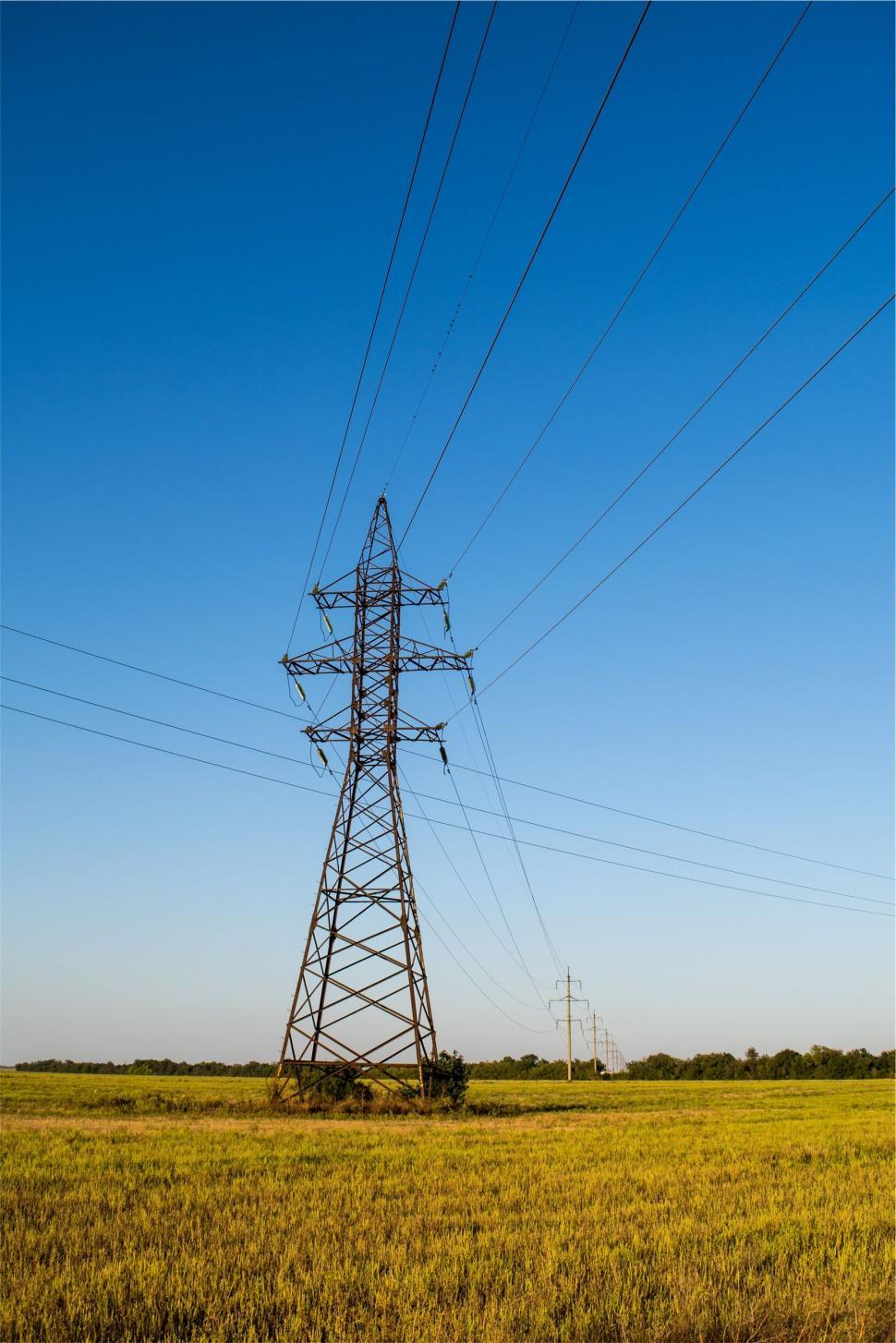 Free Image of Tall metal electricity pylon in vast green field 