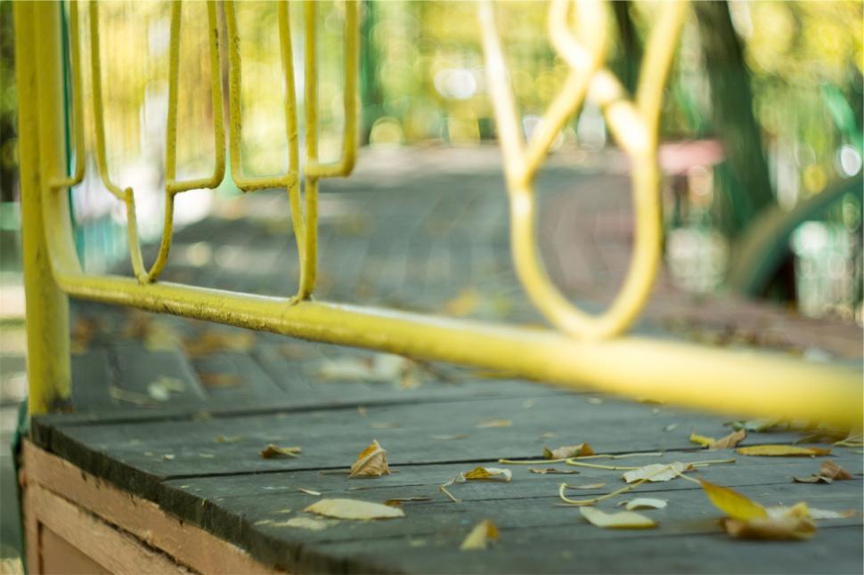 Free Image of Outdoor scene with yellow fence and fallen autumn leaves. 