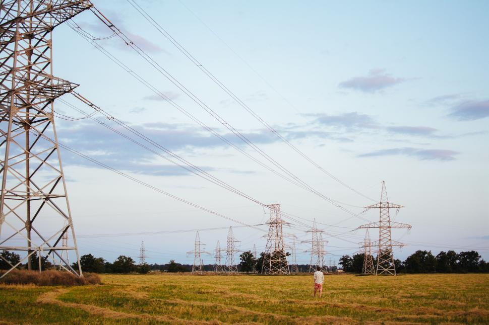Free Image of Person standing beneath high tension power lines outdoors 