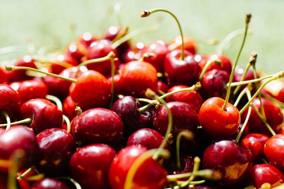 Free Image of Pile of ripe red cherries on grassy background outdoors 