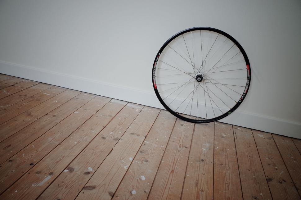 Free Image of Single bicycle wheel leaning against a plain white wall 