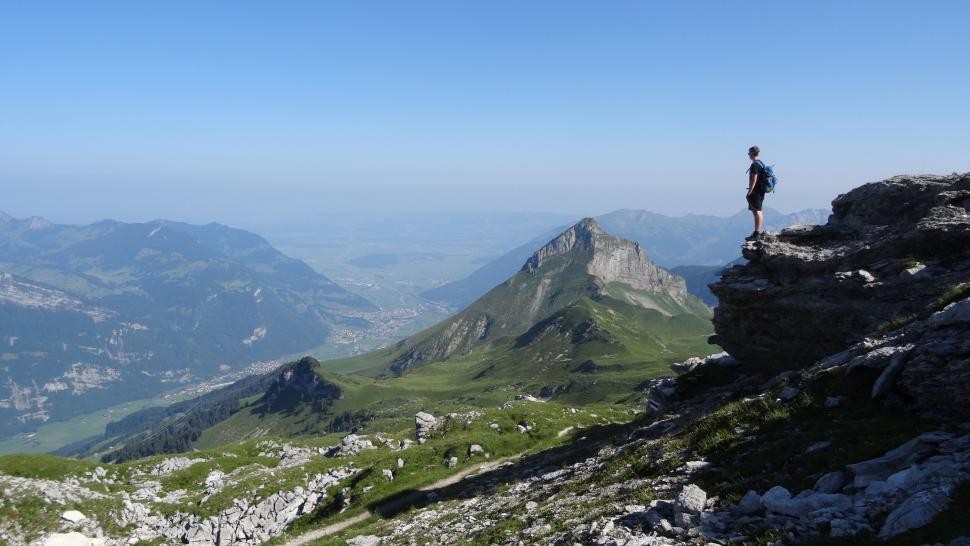Free Image of Hiker standing atop a mountain peak enjoying the view 