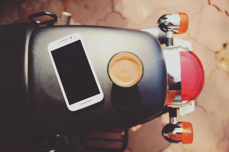 Free Image of Smartphone and Coffee Cup on Motorcycle Seat 