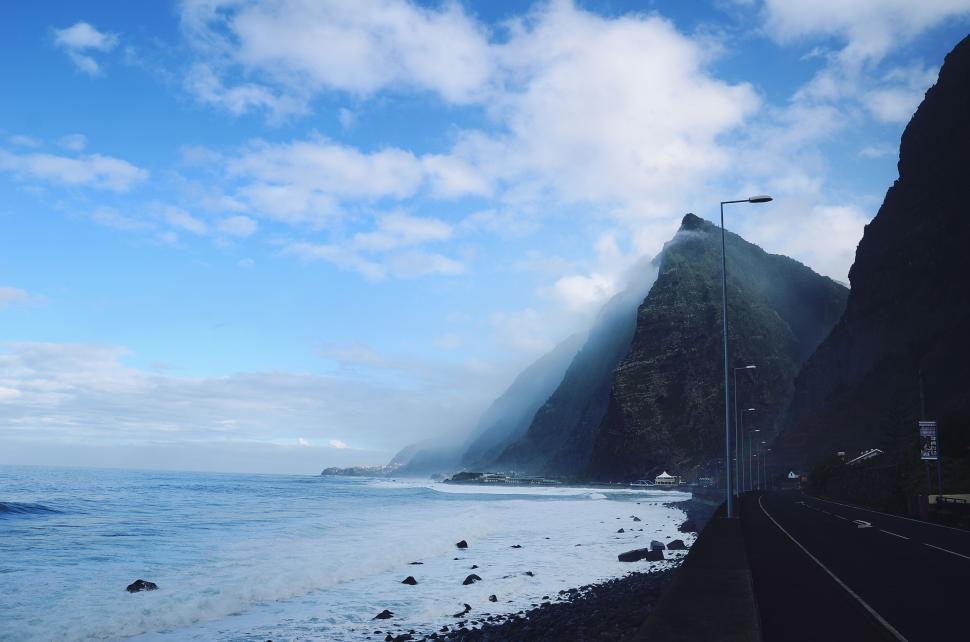 Free Image of Scenic coastal view with mountains and ocean waves. 