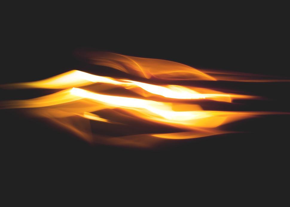 Free Image of Abstract yellow and orange light streaks on black background 