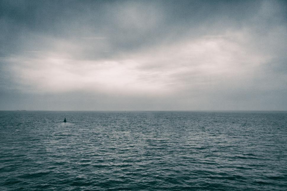 Free Image of Lone figure in a small boat on a vast, calm sea 