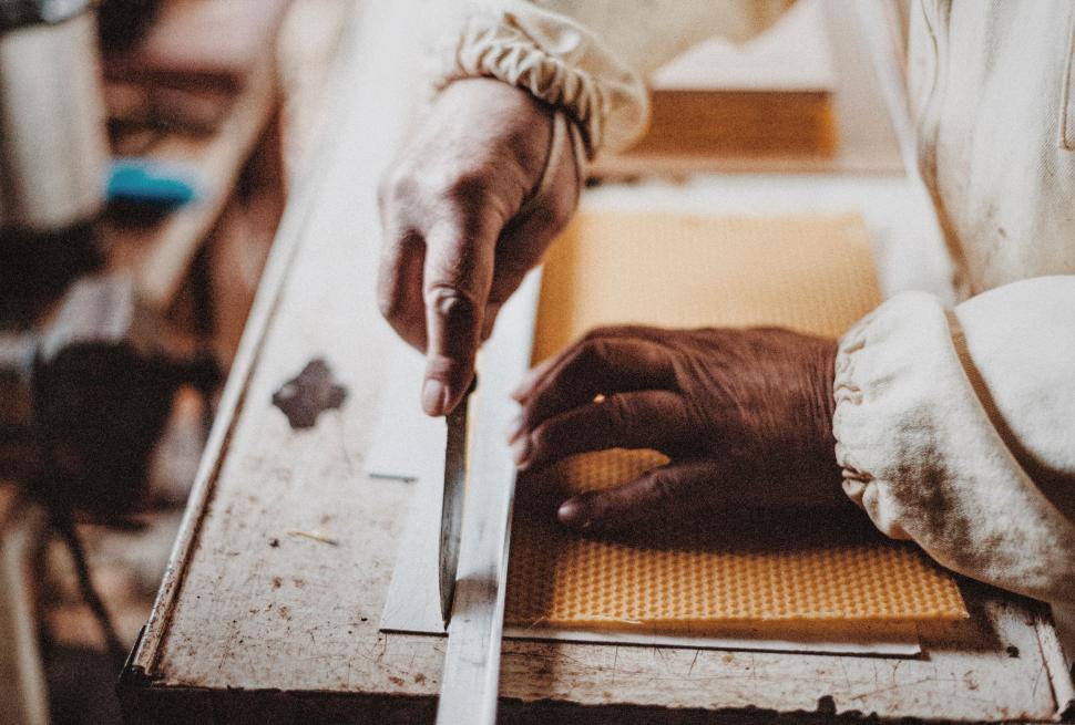 Free Image of Artisan measuring and cutting material on a workbench. 