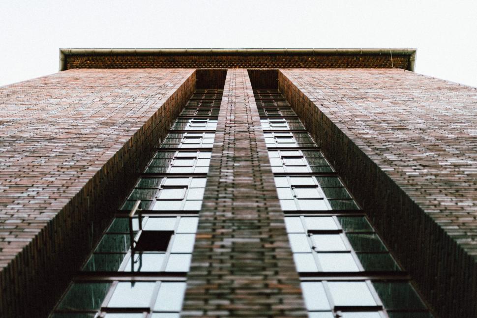 Free Image of Upward view of a tall brick building with windows 