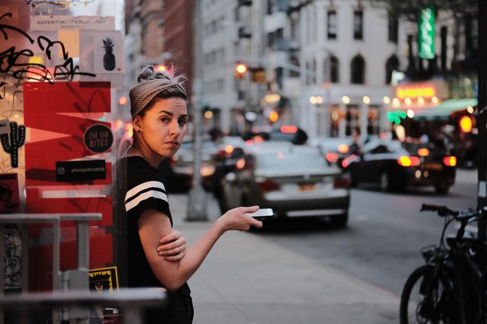 Free Image of Woman standing on a street, vivid urban backdrop. 