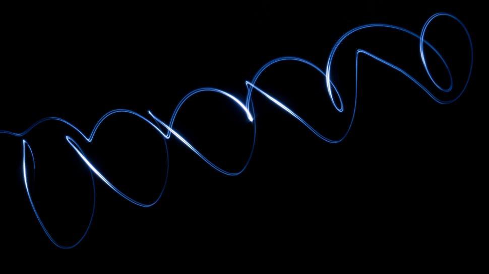 Free Image of Blue light trail in the dark forming spiral patterns 