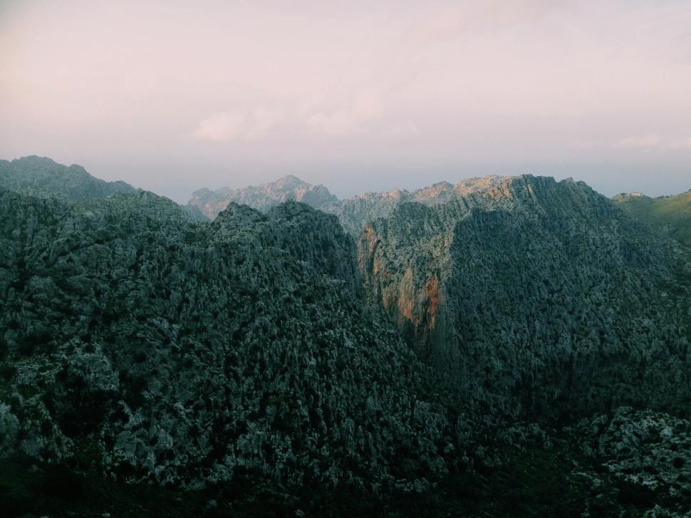 Free Image of Foggy mountain range under a softly lit sky 