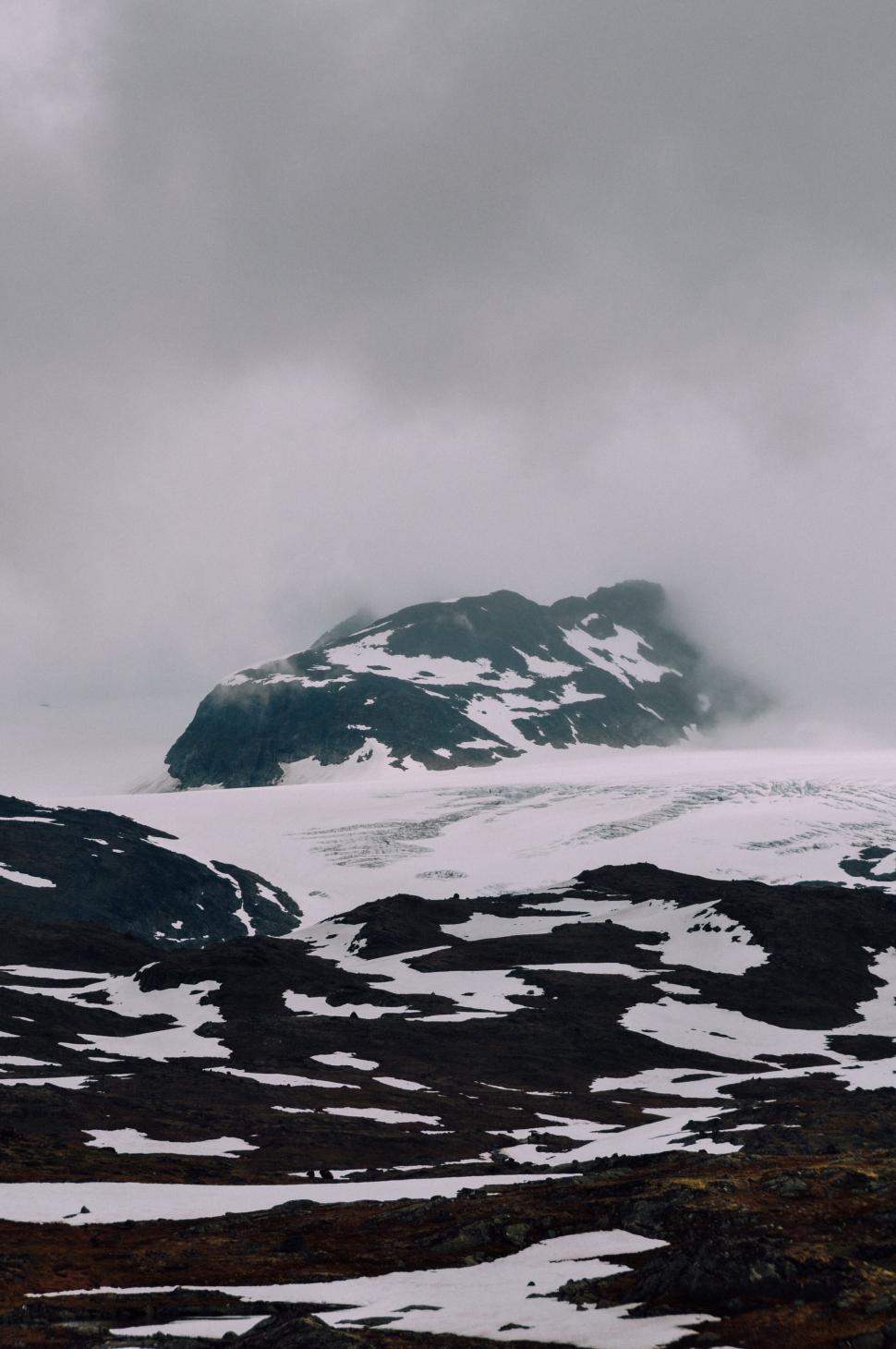Free Image of Snow-capped mountain peak partially obscured by clouds 