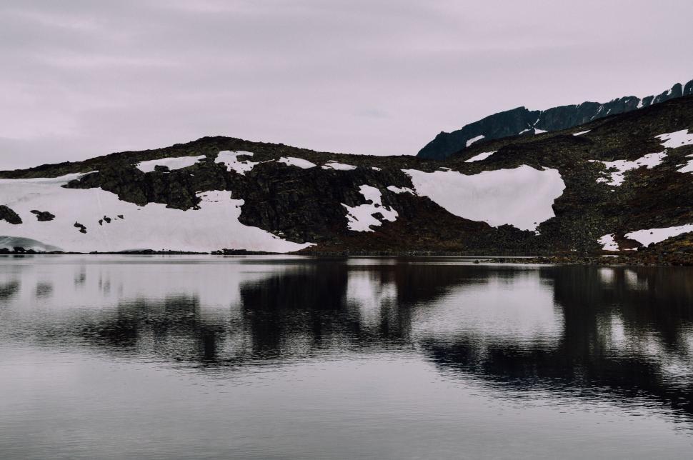 Free Image of Cold mountain lake reflecting nearby snowy peaks 