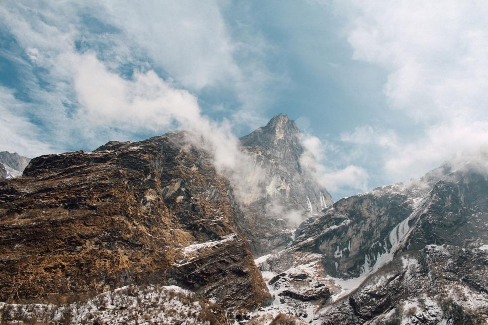 Free Image of Majestic mountains bathed in soft clouds and sunlight 