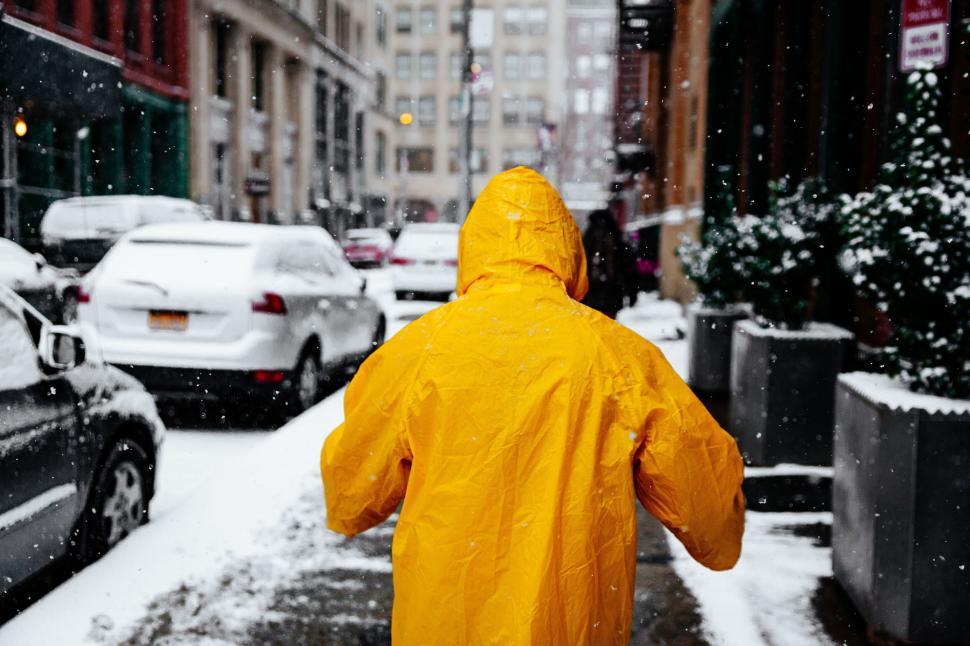 Free Image of Person in yellow raincoat walking on snowy city street 