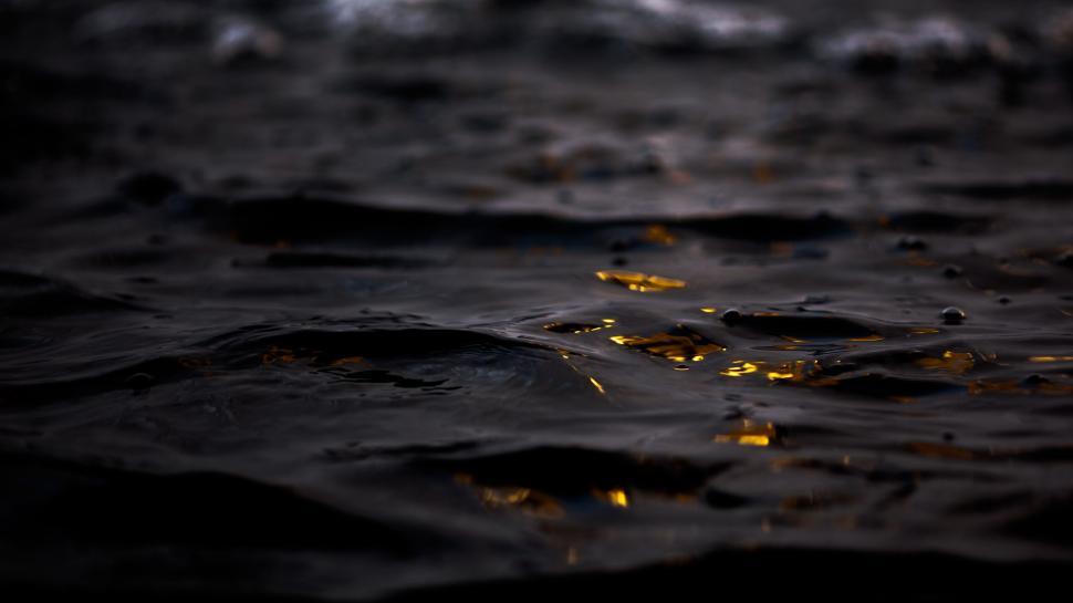 Free Image of Dark rippling water with shimmering golden reflection. 