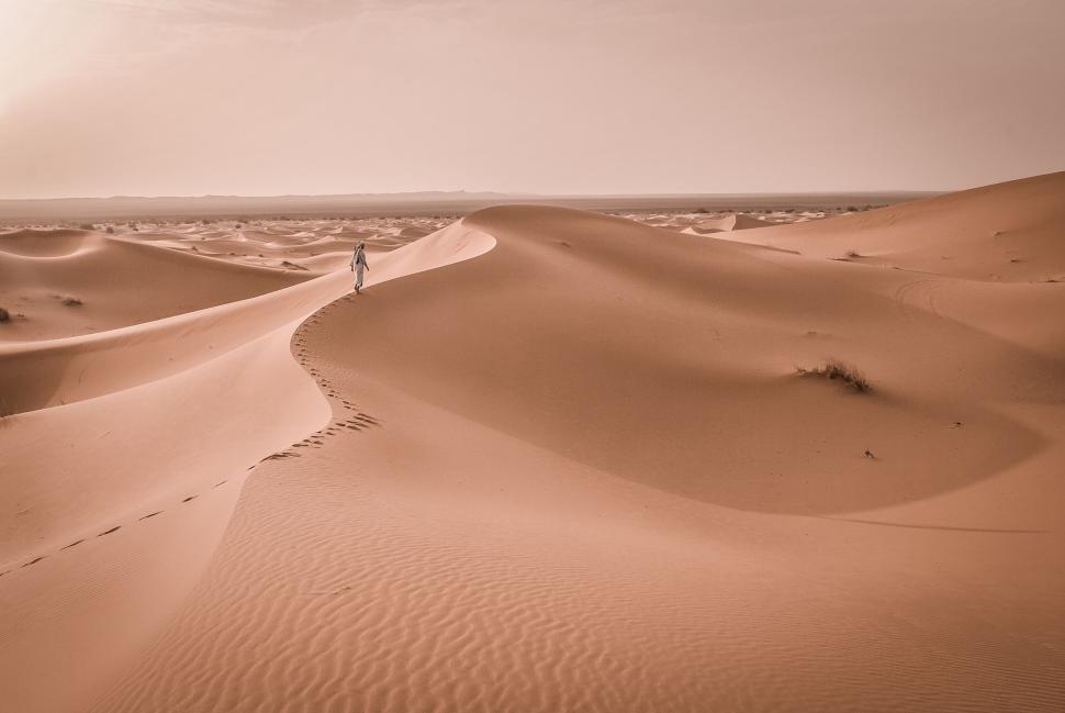 Free Image of Person walking through sand dunes in vast desert area. 