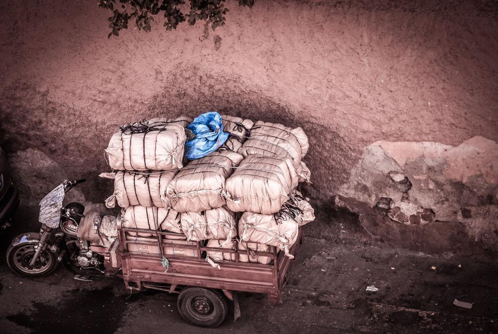 Free Image of Motorbike loaded with large sacks parked against wall. 
