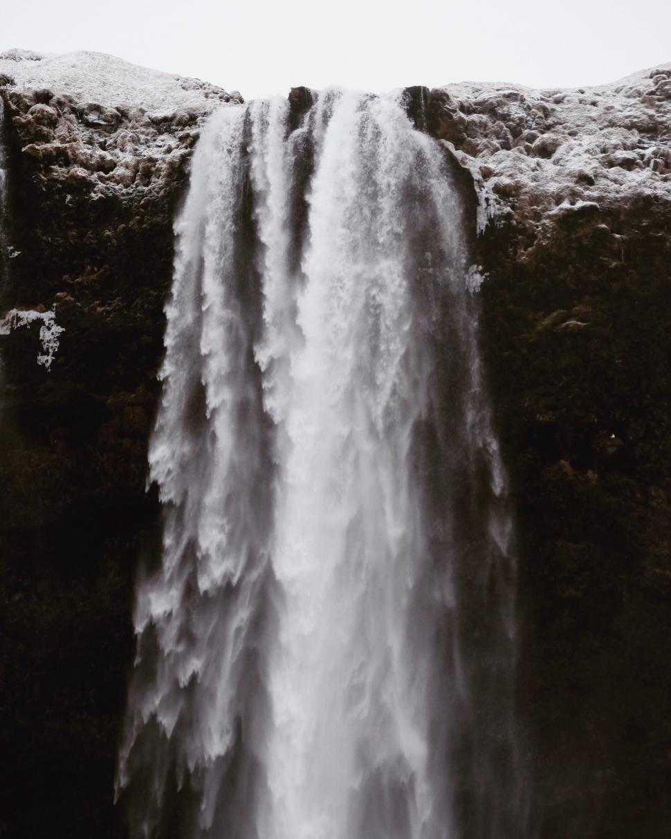 Free Image of Majestic waterfall cascading down a rugged rocky cliff 