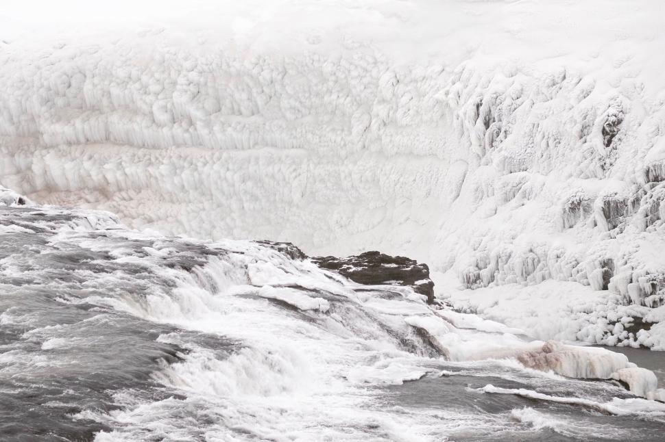 Free Image of Rushing river flows beside icy banks in harsh winter. 