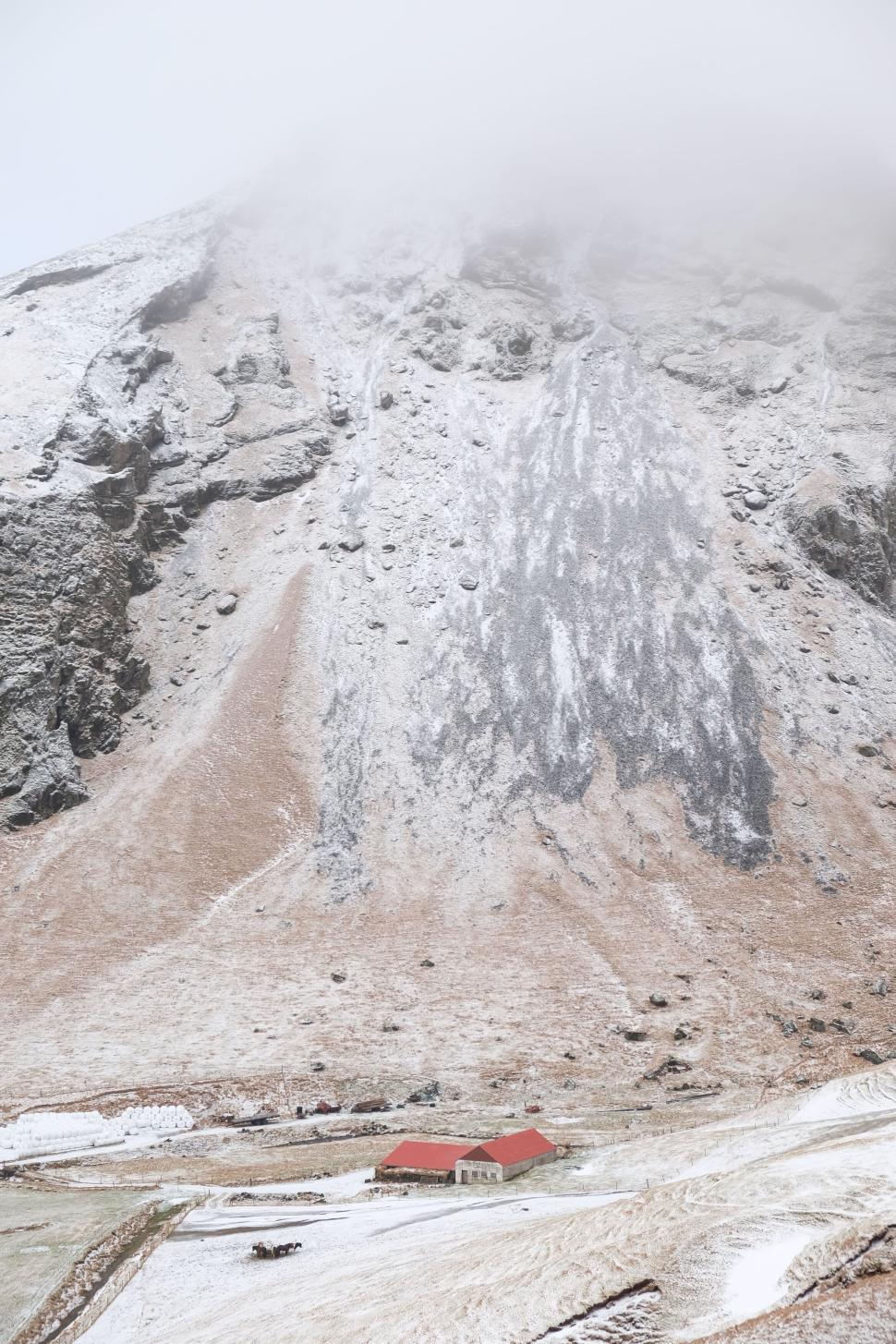 Free Image of Mountain with snow and a small red-roofed building low 