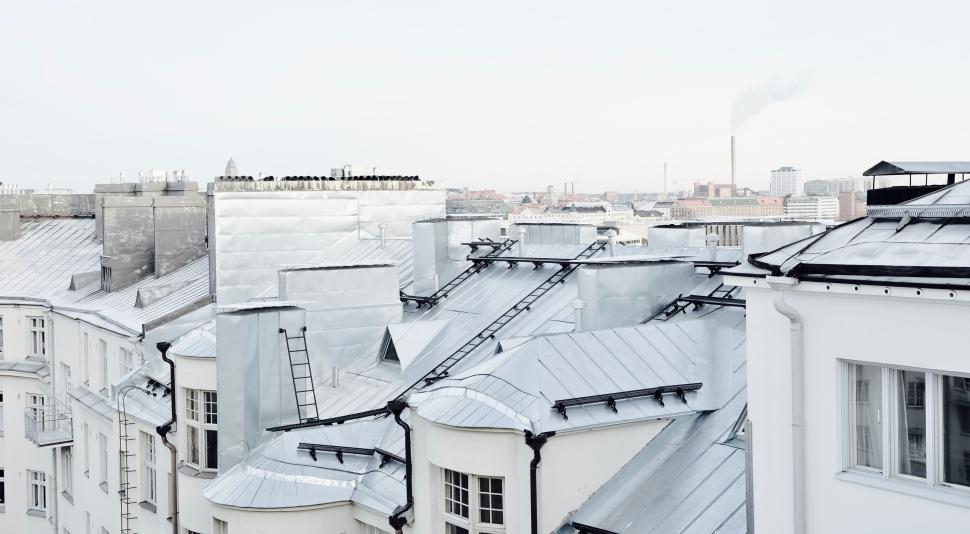 Free Image of Urban rooftops with smoke stacks and industrial backdrop 