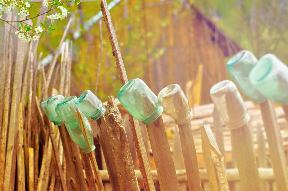 Free Image of Old fence decorated with glass jars in a rustic setting. 