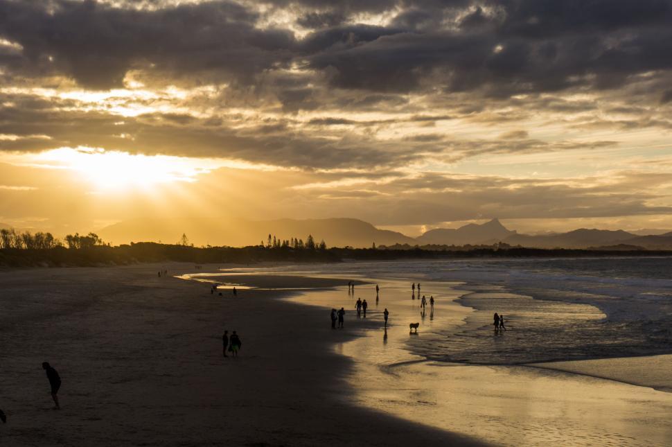 Free Image of Sunset beach with people and reflections on wet sand 