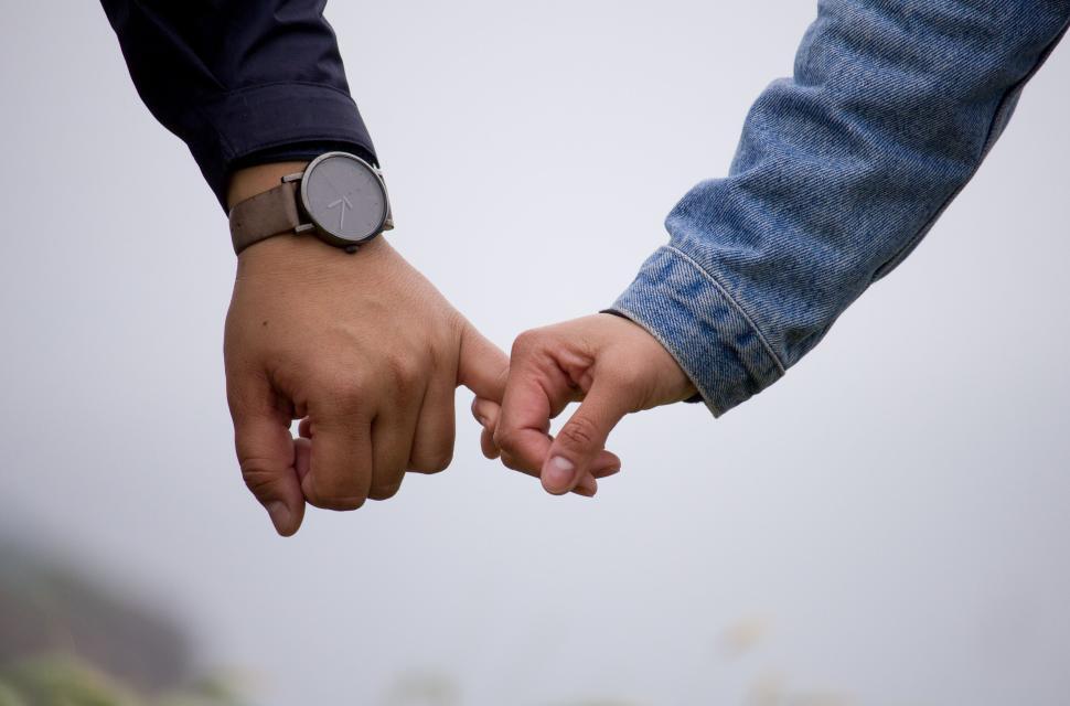 Free Image of Two hands gently touching with fingers interlocked. 