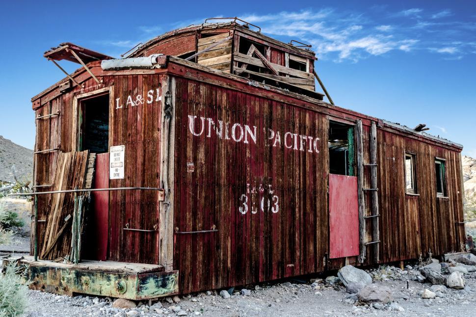 Free Image of Old wooden train car in desert landscape with clear sky. 