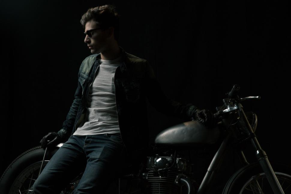 Free Image of Person seated on motorcycle in a darkened setting. 