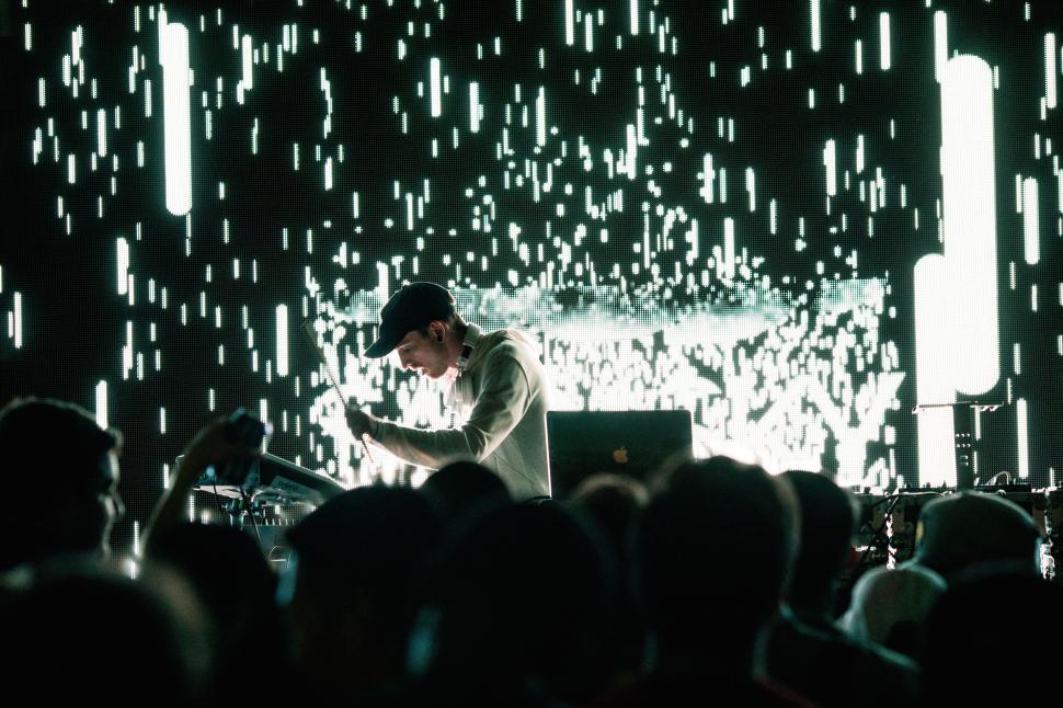 Free Image of Concert performer on stage with illuminated backdrop. 