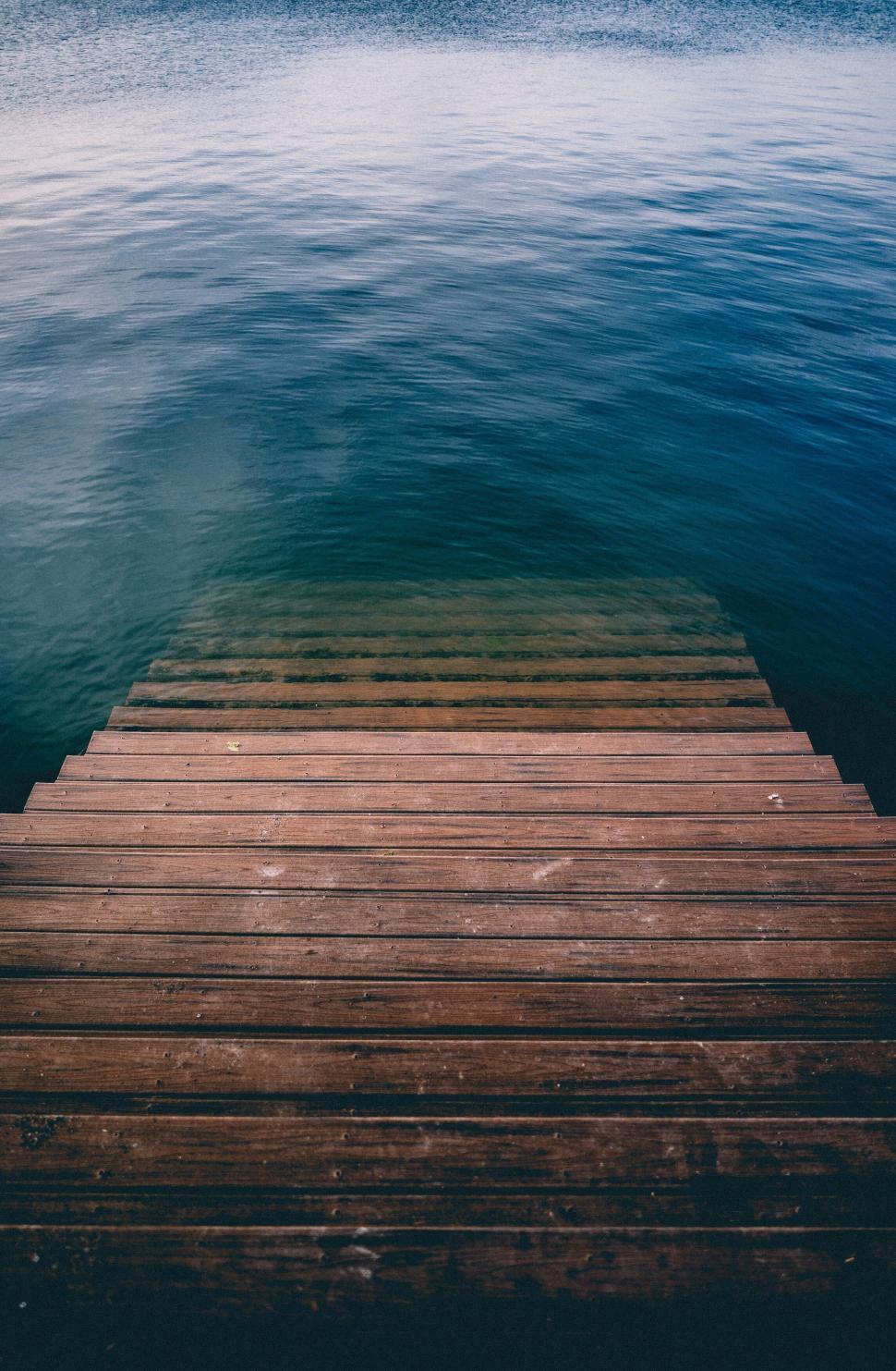 Free Image of Wooden steps descending into calm and serene waters. 