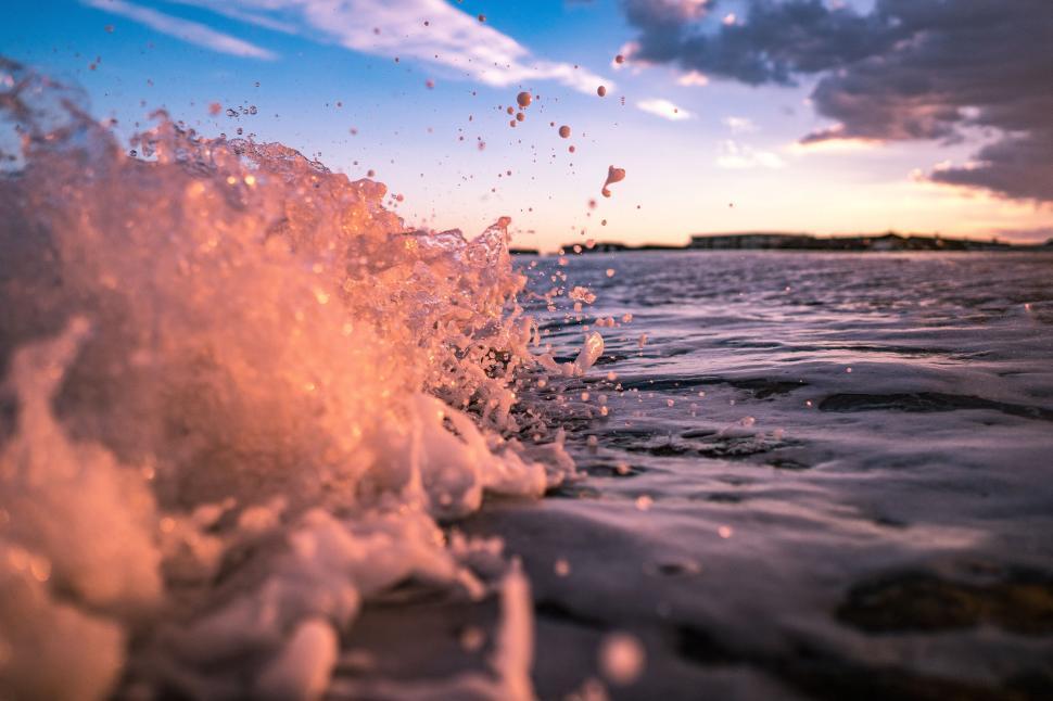 Free Image of Waves crashing with splash at sunset over ocean surface. 
