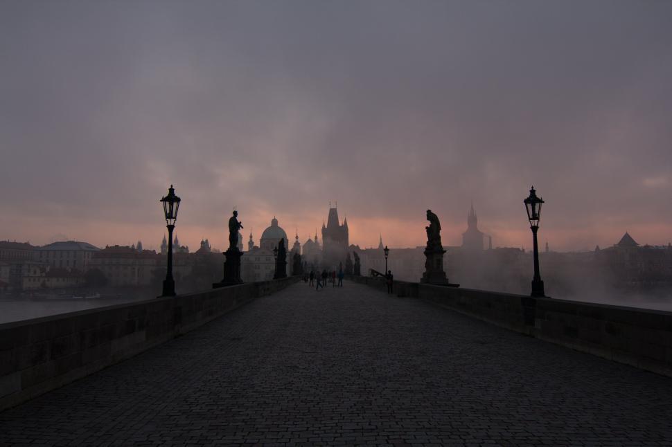 Free Image of Silhouetted figures on ancient bridge at misty twilight. 
