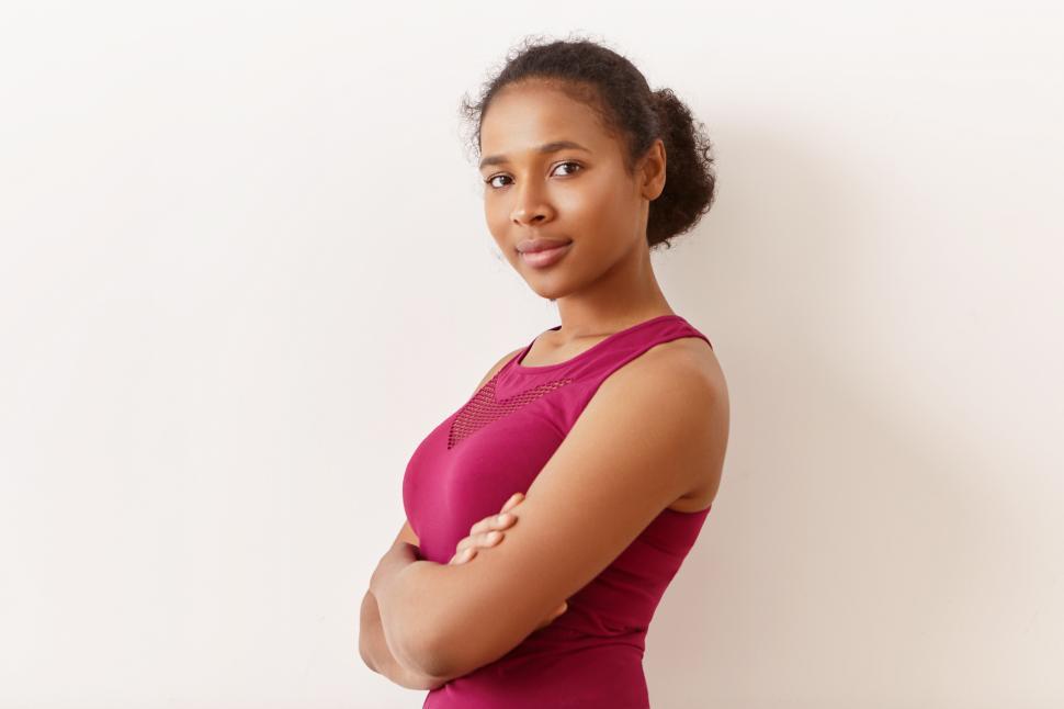 Free Image of Half profile shot of good looking beautiful young African female with black hair gathered in bun having confident facial expression, crossing arms on her chest. People, style, sports and fitness 