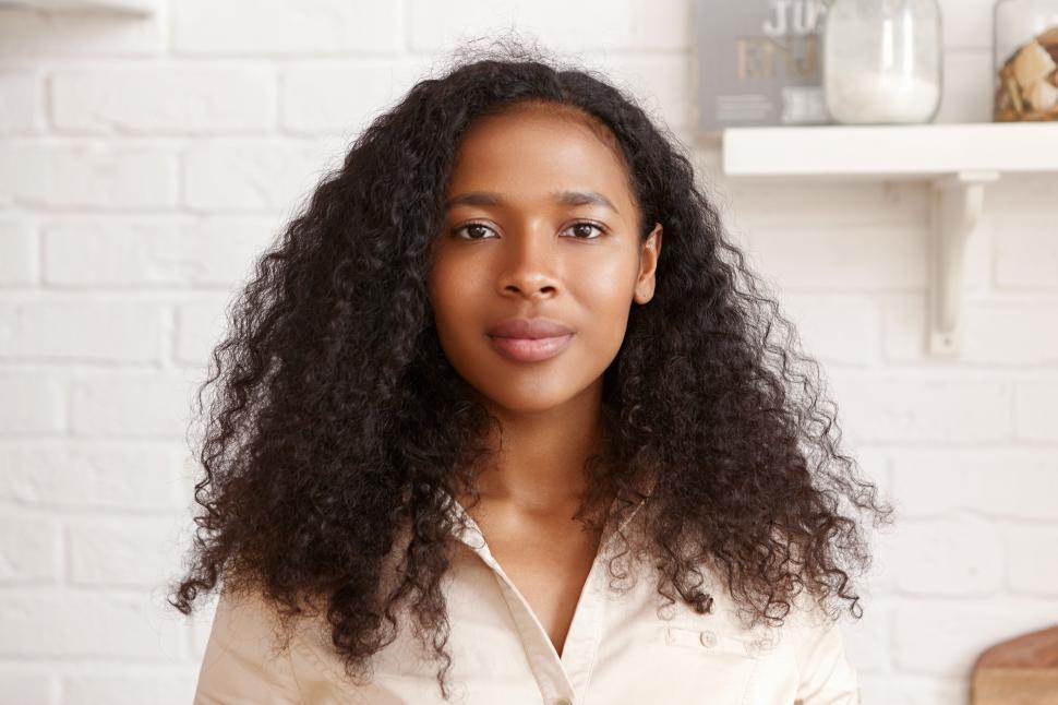 Free Image of People, lifestyle, domesticity and household concept. Portrait of good looking gorgeous young dark skinned female with curly loose hair, big lips and shiny perfect skin posing indoors in kitchen 