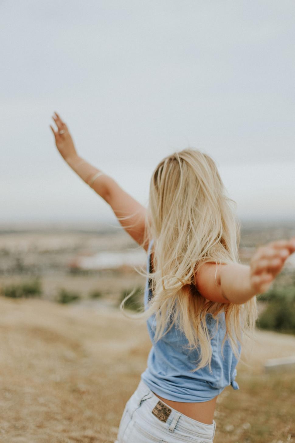 Free Image of Woman in blue top enjoying view with arms outstretched 