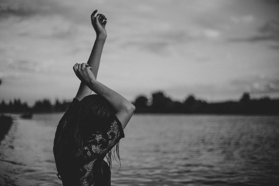Free Image of Silhouette of woman with arms raised beside water body 