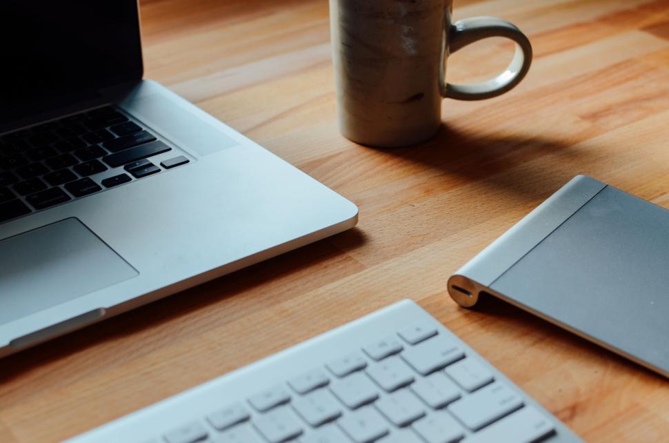 Free Image of Laptop, keyboard, and mug on a wooden desk workspace. 