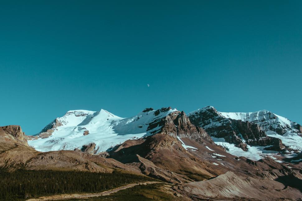 Free Image of Snow-capped mountains under clear blue sky horizon. 