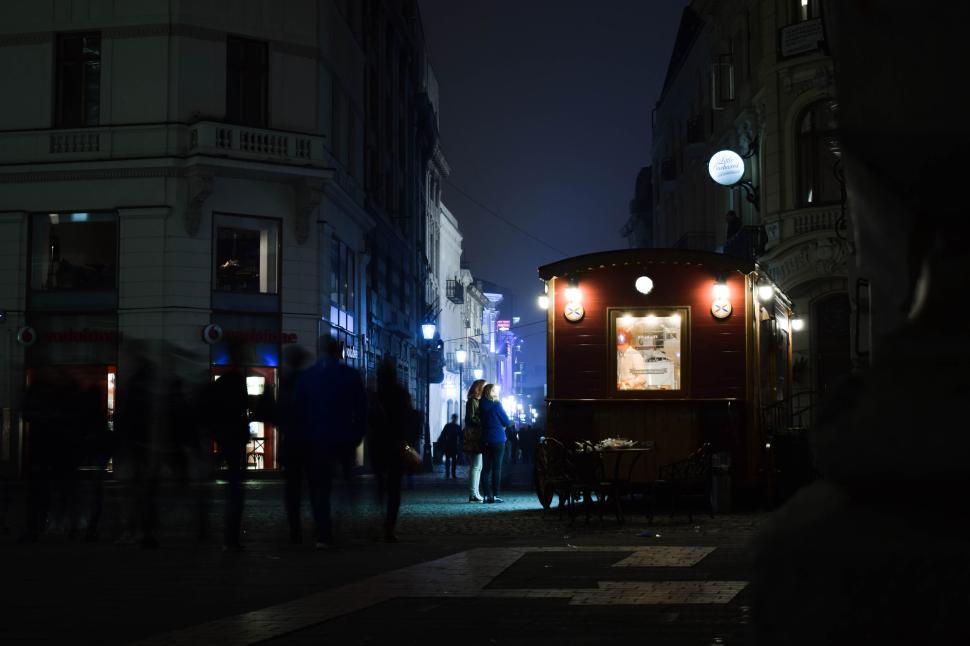 Free Image of Night scene in city with lights, cafe, and people. 