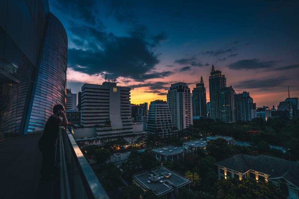 Free Image of Man gazing city from terrace during beautiful sunset 