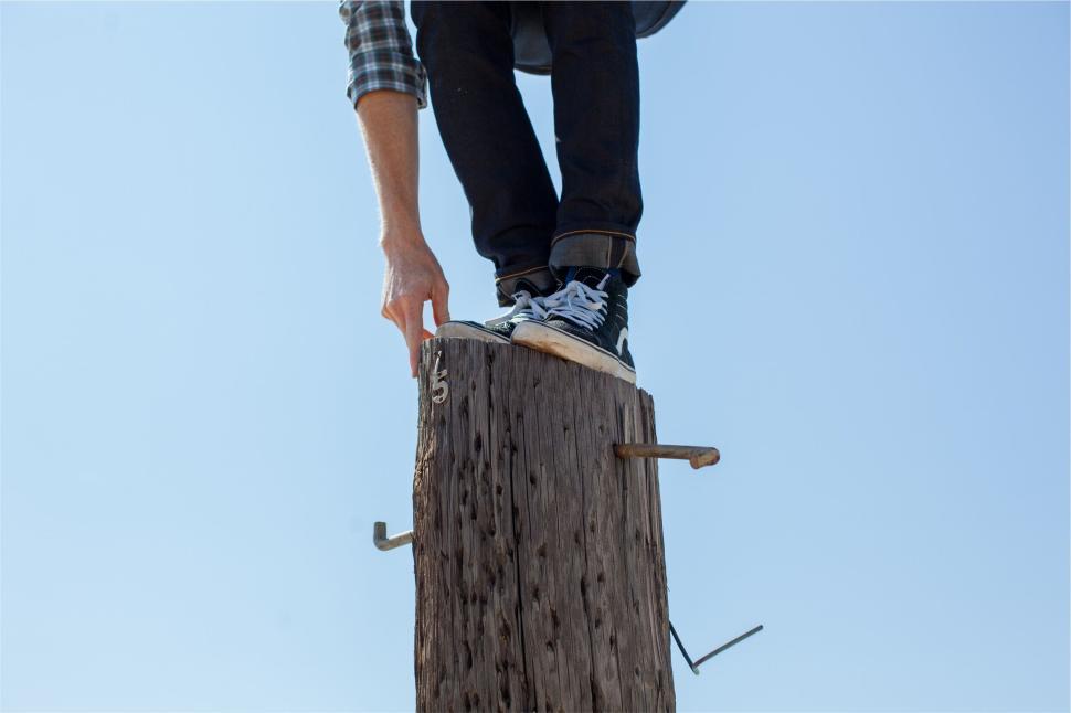 Free Image of Person balancing on tall post with blue sky background 