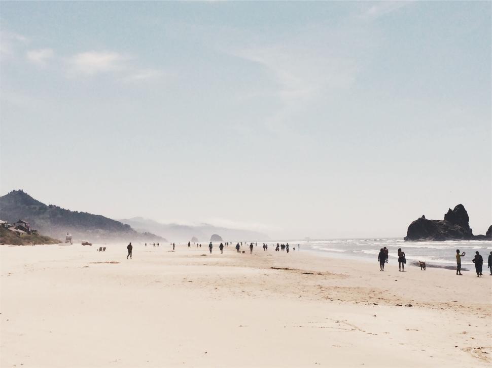 Free Image of People walking along a sandy beach on a sunny day 