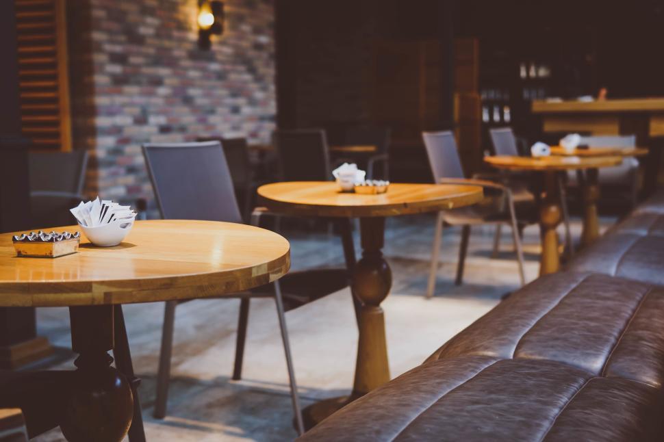 Free Image of Empty cafe with wooden tables and chairs serene view. 