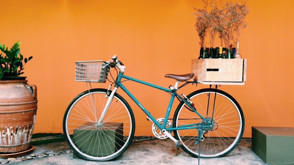 Free Image of Blue bike with basket and crate against orange wall. 