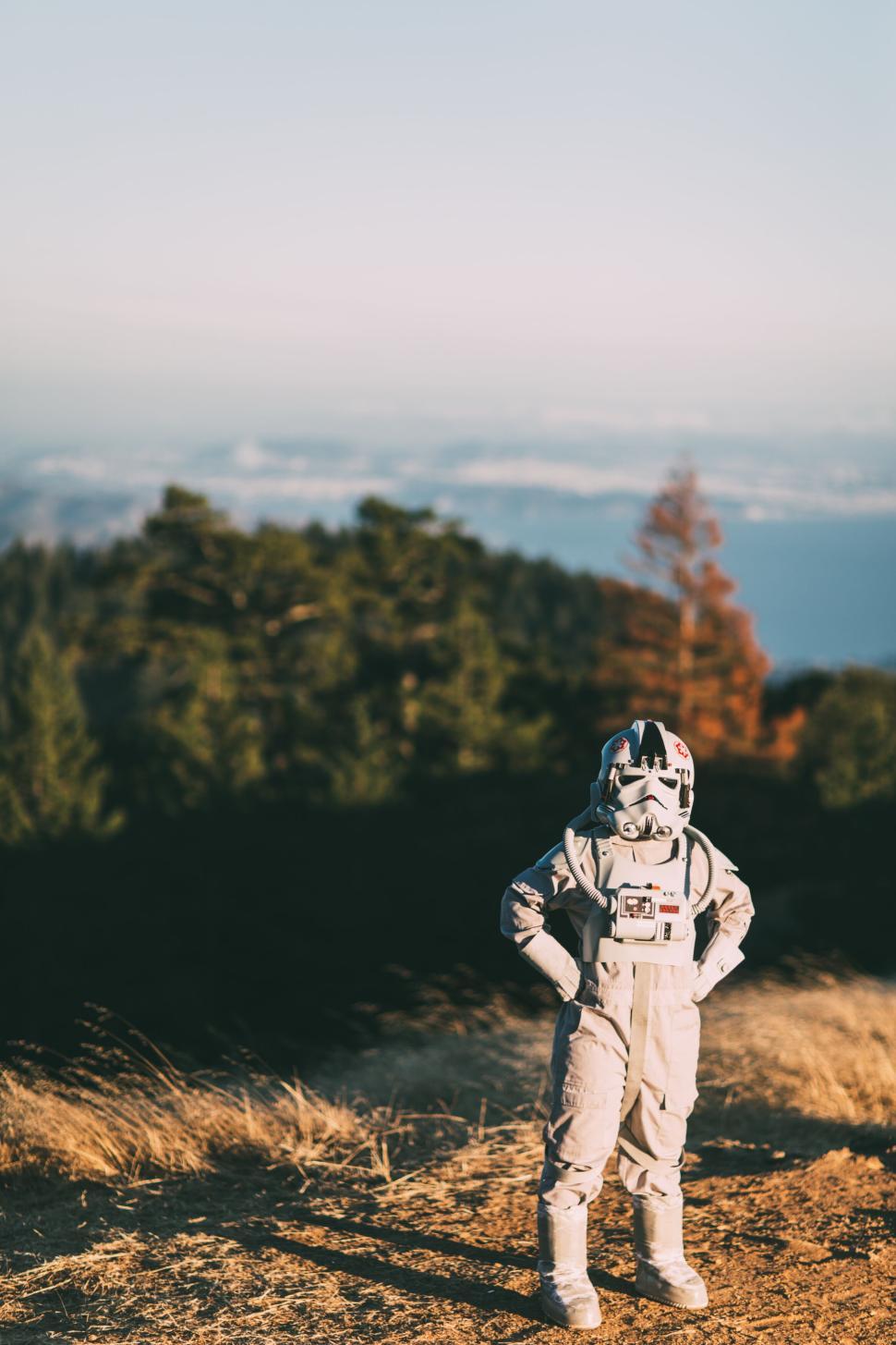 Free Image of Person in silver spacesuit standing on hillside with view. 