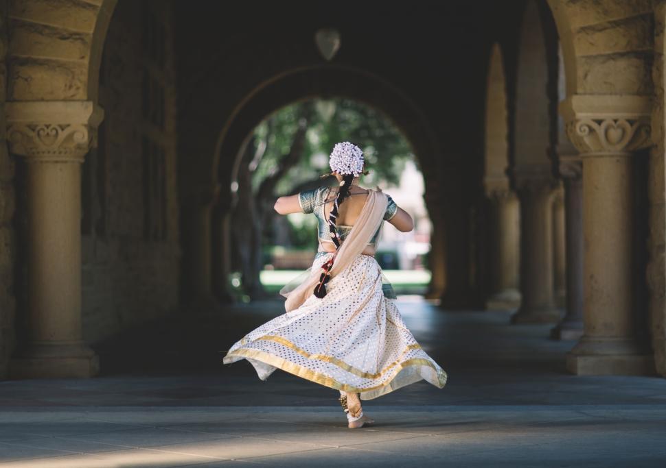Free Image of Dancer in white traditional attire spins gracefully outdoors. 
