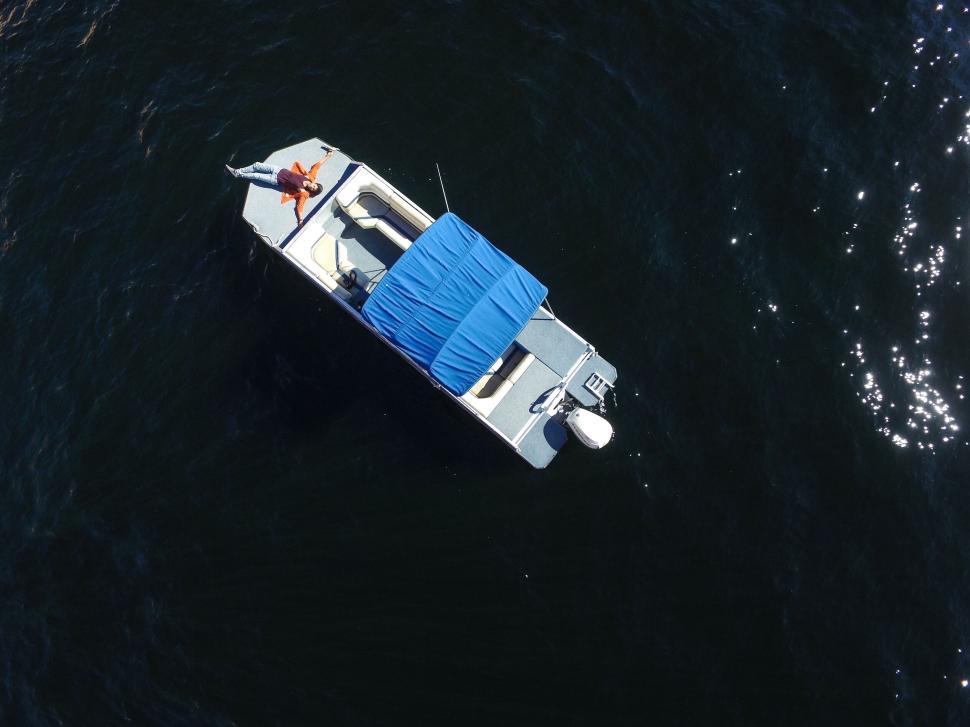 Free Image of Aerial view of a blue-topped boat afloat on the water. 